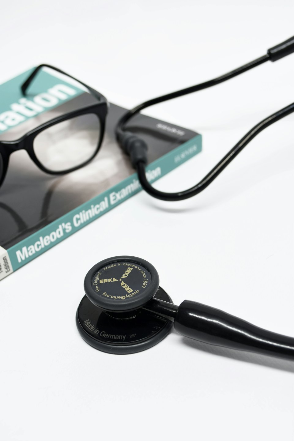 Stethoscope and glasses rest on a medical textbook.